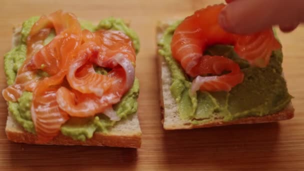 Ahşap Bir Kesme Tahtasının Üzerinde Duran Gaucamole Somonlu Sandviçin Yakın — Stok video