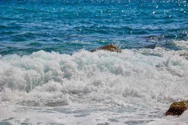 Dalgalar gün boyunca Akdeniz kıyılarında kayalara çarpıp çarpıyor. Cala del Moraig plajı Benitachell, Alicante, İspanya.