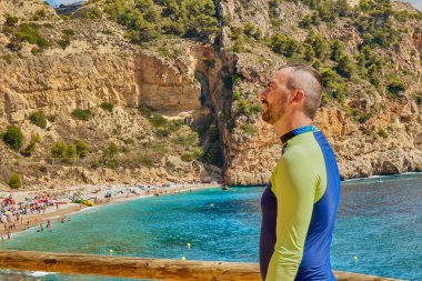 Terasta güzel bir sahili olan yakışıklı bir adam duruyor. Cala del Moraig plajı, Benitatxell, Alicante, İspanya.