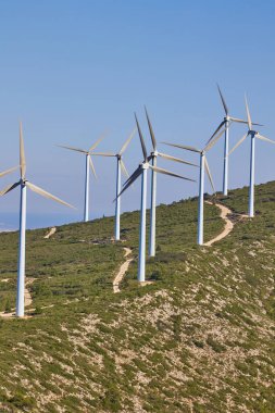 Güneşli yaz manzarasında rüzgar türbinleri. Dağ rüzgar parkında virajlı yol. Yeşil ekolojik enerji üretimi. Bunol rüzgar çiftliği, İspanya.