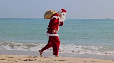 Omzunda hediyelerle dolu bir çantayla Noel Baba sıcak bir yaz gününde dalgalar boyunca kumlu sahil boyunca yürür. Sıcak ülkelerde Noel ya da yeni yıl tatili. Noel Baba 'nın yaz tatili.
