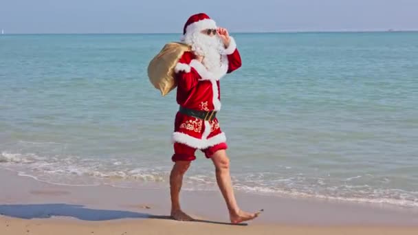 Santa Claus Con Una Bolsa Regalos Hombro Camina Largo Playa — Vídeo de stock