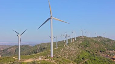 Güneşli yaz manzarasında rüzgar türbinleri. Dağ rüzgar parkında virajlı yol. Yeşil ekolojik enerji üretimi. Bunol rüzgar çiftliği, İspanya.