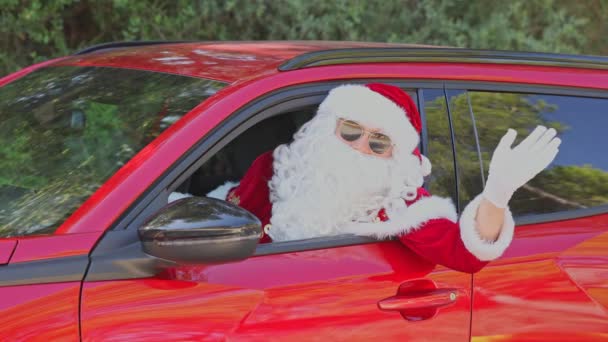 Noel Baba Kafasını Kırmızı Bir Arabanın Camından Çıkarıp Elini Sallıyor — Stok video