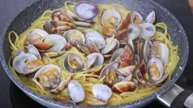 İstiridyeli geleneksel İtalyan deniz ürünleri makarnası pişiriyorum. Maydanoz ekliyorum. Spagetti alle Vongole.