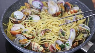 İstiridyeli geleneksel İtalyan deniz ürünleri makarnası pişiriyorum. Şef spagettiyi servis için kıvırıyor. Spagetti alle Vongole.