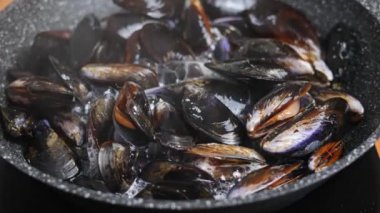 Evde kızartma tavasında Akdeniz midyesi pişirmek. Yavaş döndürme.