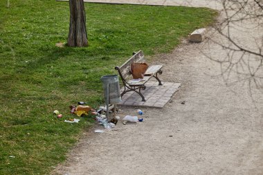 Parktaki bankta ve çöp tenekesinde. Çöp bankın üstüne ve çöp kutusunun etrafına atılır..