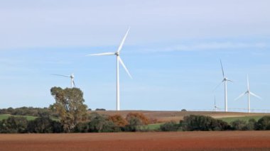 Tarımsal alanlarda açık mavi gökyüzüne karşı rüzgar türbinleri. Rüzgar türbinleri zayıf bir rüzgarda yavaşça döner. Yeşil ekolojik enerji üretimi, İspanya.