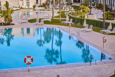 Sabahın erken saatlerinde, deniz kenarındaki bir otelde boş bir havuz..