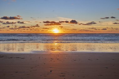 Dramatik deniz batımı. Batan güneş denize batar. Sakin dalgalar kumsalda yuvarlanıyor.