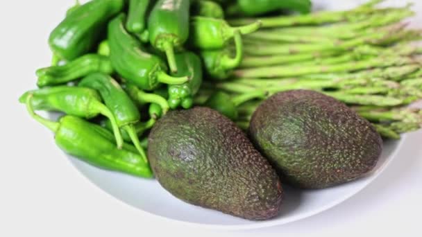 緑の野菜は皿の上に回っている アボカド アスパラガス 唐辛子 — ストック動画