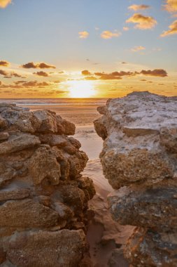 Dramatik deniz batımı. Batan güneş denize batar. Sakin dalgalar kumsalda yuvarlanıyor.