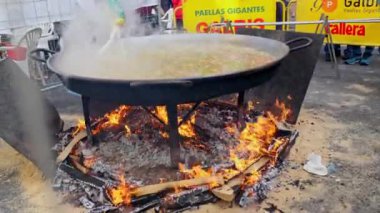 Las Fallas Festivali sırasında geleneksel büyük bir tavada lezzetli bir paella hazırlıyor. Valencia, İspanya - 16 Mart 2024.