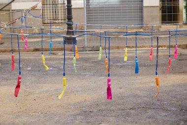 Şehir caddesinde havai fişekler sallanıyor. Las Fallas sırasında maske takmadan önce şehir caddesinde asılı duran renkli havai fişekler. Valencia, İspanya - 17 Mart 2024.