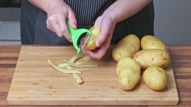 Patates soyan bir kadının elleri. Evde yemek pişirmek..