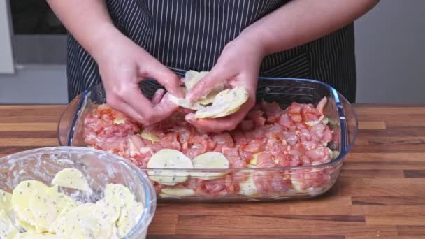 女人把土豆放在玻璃器皿里的鸡肉上 在家做饭 — 图库视频影像