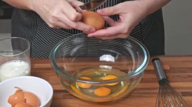 Dişi eller bir bıçakla yumurta kırar. Bir kadın cam kaseye yumurta kırıyor..