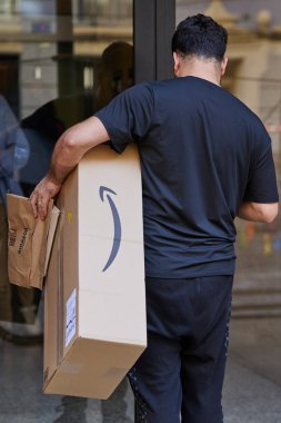 Amazon 'dan gelen paketli bir kurye evin önünde duruyor. Arkadan bak. Valencia, İspanya - 17 Mart 2024.