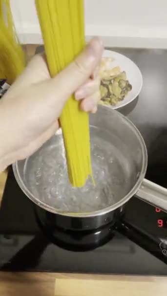 女人用海鲜煮意大利面 把意大利面放在一壶开水里 — 图库视频影像