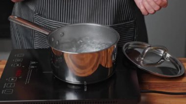 Bir kadın kaynar suya spagetti atıyor.