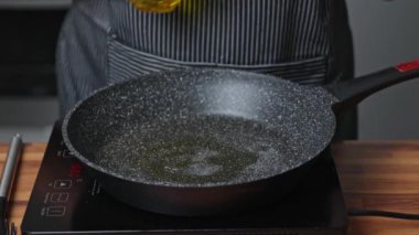Bir kadın kızartma tavasında soğan ve kurutulmuş domates kızartıyor.
