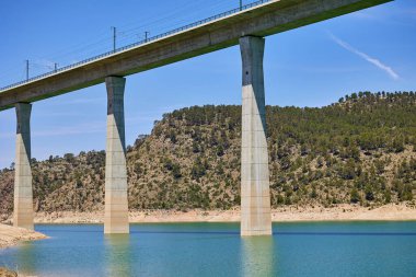 Explore the tranquil scene under the bridge Viaducto de Contreras through reservoir. clipart