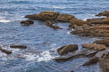 Bir deniz dalgası kıyı kayalıklarında yuvarlanıyor..