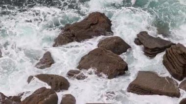 Bir deniz dalgası kıyı kayalıklarında yuvarlanıyor..