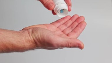 Bir adam eline ilaç şişesinden ilaç döker.