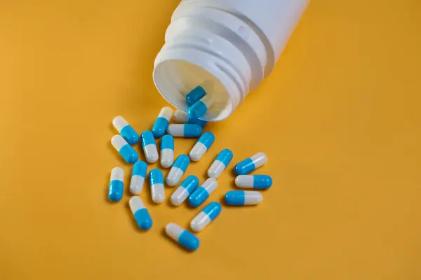 Kapsülleri dökülmüş reçeteli ilaç şişesinin yakın çekimi..