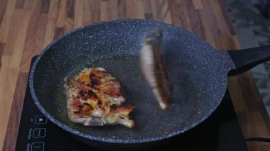 Bir kadın tavada iki parça et kızartır.