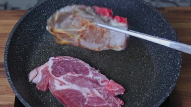 Bir kadın tavada iki parça et kızartır.