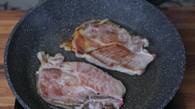 Bir kadın tavada iki parça et kızartır.