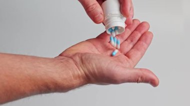 Bir adam eline ilaç şişesinden ilaç döker.