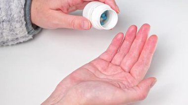 Bir kadın eline ilaç şişesinden ilaç dolduruyor.