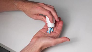 Bir adam eline ilaç şişesinden ilaç döker.