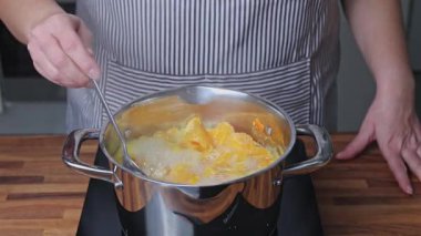 Ev mutfağındaki ocakta tencerede mandalina reçeli pişirmek.