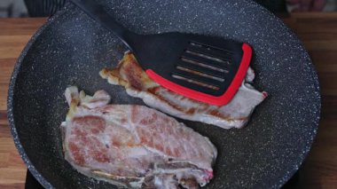 Bir kadın tavada iki parça et kızartır.