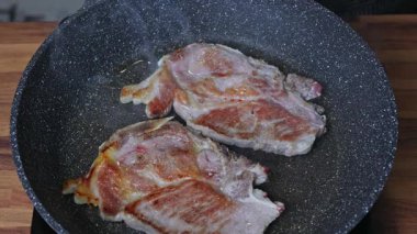 Bir kadın tavada iki parça et kızartır.