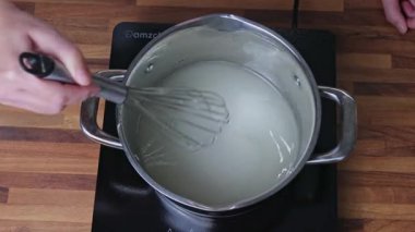 Ev mutfağındaki bir tencerede mandalina reçeli pişirmek için şeker şurubu hazırlıyorum.