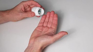 Bir adam eline ilaç şişesinden ilaç döker. 