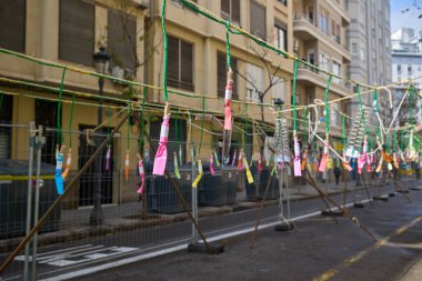 Şehir caddesinde havai fişekler sallanıyor. Las Fallas sırasında maske takmadan önce şehir caddesinde asılı duran renkli havai fişekler. Valencia, İspanya - 17 Mart 2024.
