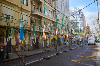 Şehir caddesinde havai fişekler sallanıyor. Las Fallas sırasında maske takmadan önce şehir caddesinde asılı duran renkli havai fişekler. Valencia, İspanya - 17 Mart 2024.
