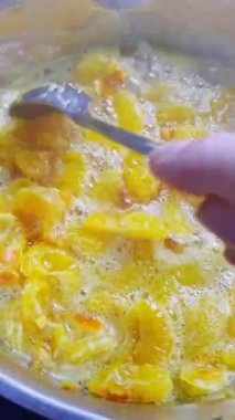 Ev mutfağındaki ocakta tencerede mandalina reçeli pişirmek.