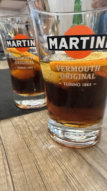 İki bardak kırmızı vermut, rahat bir barda, ahşap bir masada portakal dilimleri. Valencia, İspanya - 14 Mayıs 2025