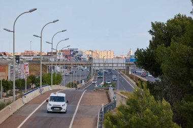 Arabalı şehir otoyolu ve gün batımında şehir silueti. Valencia, İspanya - 11 Mayıs 2025.