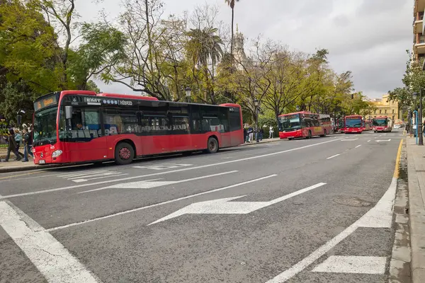 Valencia 'daki kırmızı EMT otobüsleri bulutlu bir günde şehir merkezinde bir cadde boyunca dizilmişti. Valencia, İspanya - 17 Mart 2025.