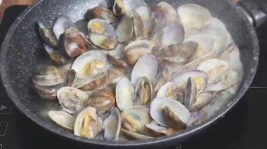 Evde tavada istiridye pişirmek. Beyaz şarapta kaynayan istiridyelerin yakın çekimi.