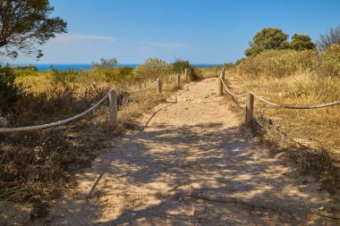 İspanya 'nın Xabia kenti yakınlarındaki Cape Sant Antoni Burnu' nda turist yürüyüş yolu. İp ve ahşap direklerle çevrili, Akdeniz kıyılarına bakan berrak mavi gökyüzü altında.